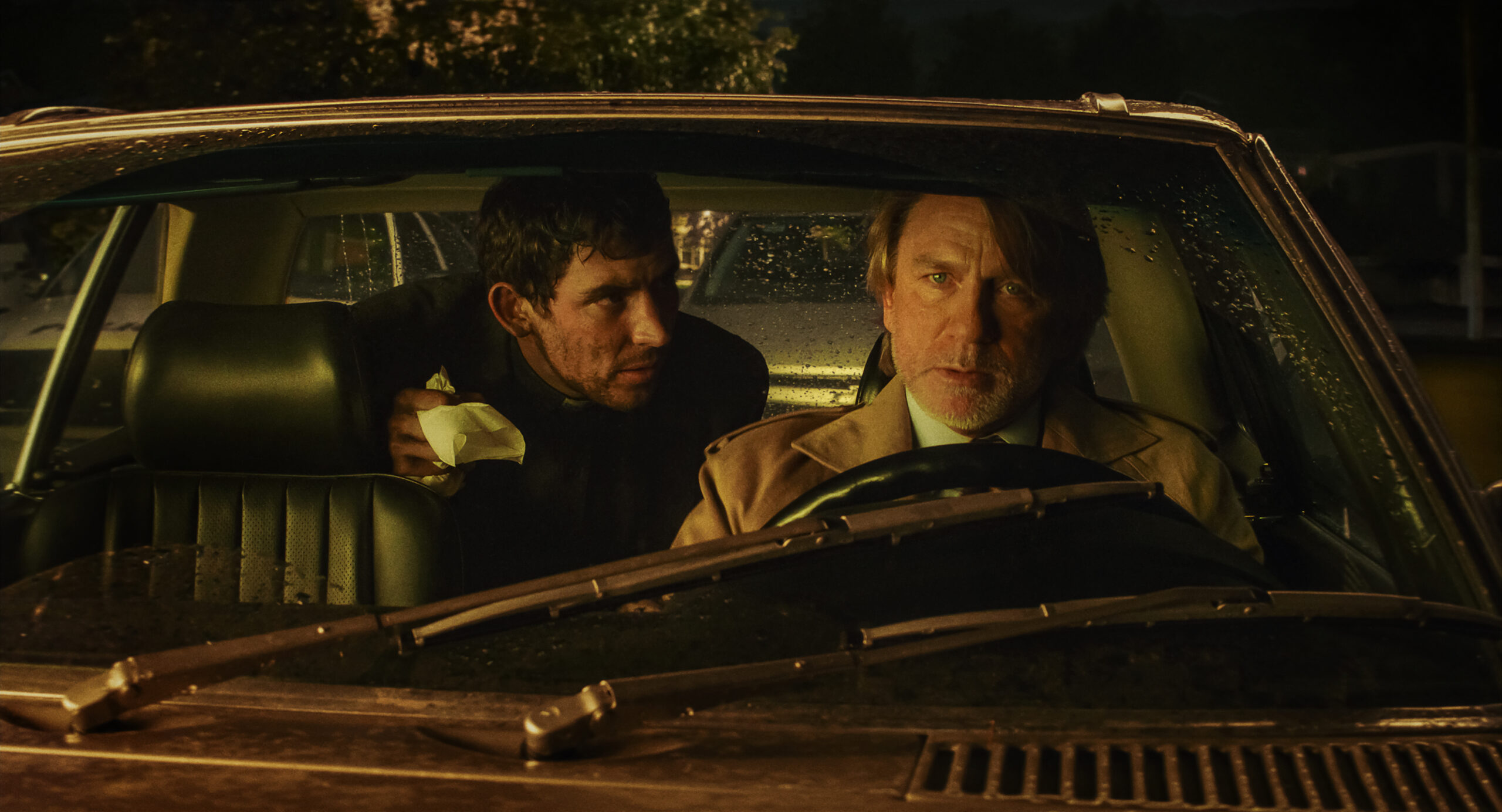 Josh O'Connor and Daniel Craig sit in a car in the new mystery film Wake Up Dead Man
