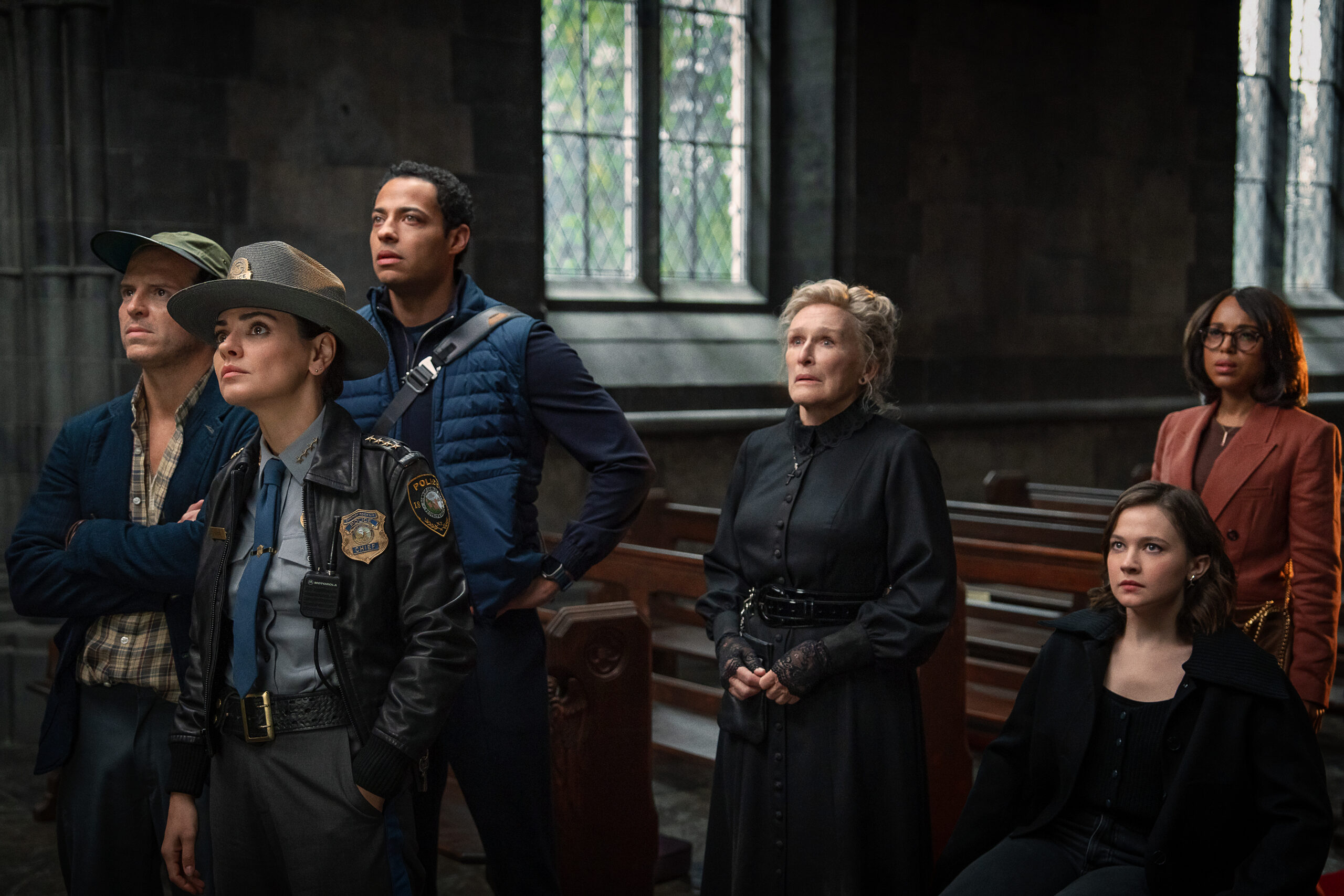 Andrew Scott, Mila Kunis, Glenn Close, and Kerry Washington standing in a church in the new mystery film Wake Up Dead Man.