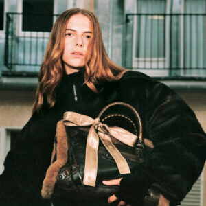 Portrait of a woman wearing the Balenciaga ski collection fleece, fingerless gloves, carrying Le City bag