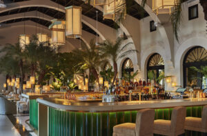 An Art Deco bar with chandeliers, palm trees, and archways.