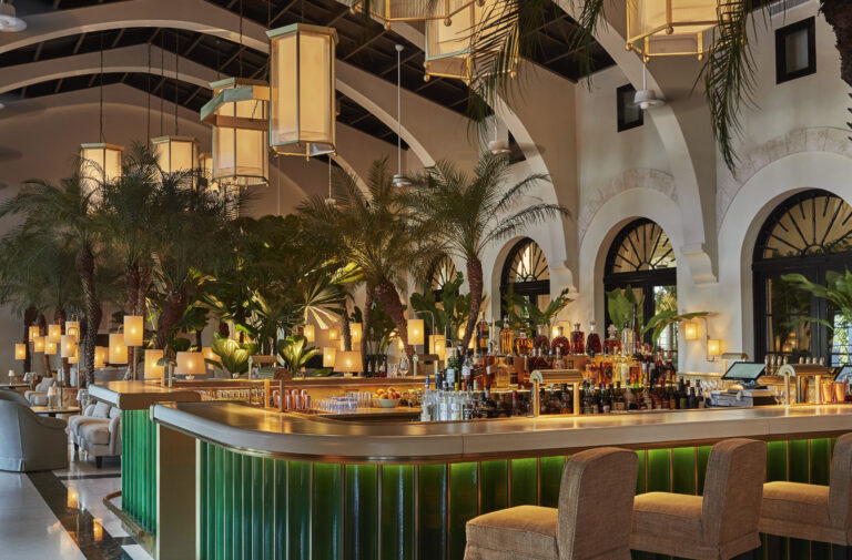 An Art Deco bar with chandeliers, palm trees, and archways.