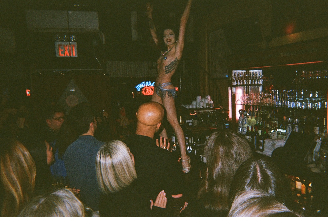 A burlesque dancer finishing their dance atop the bar