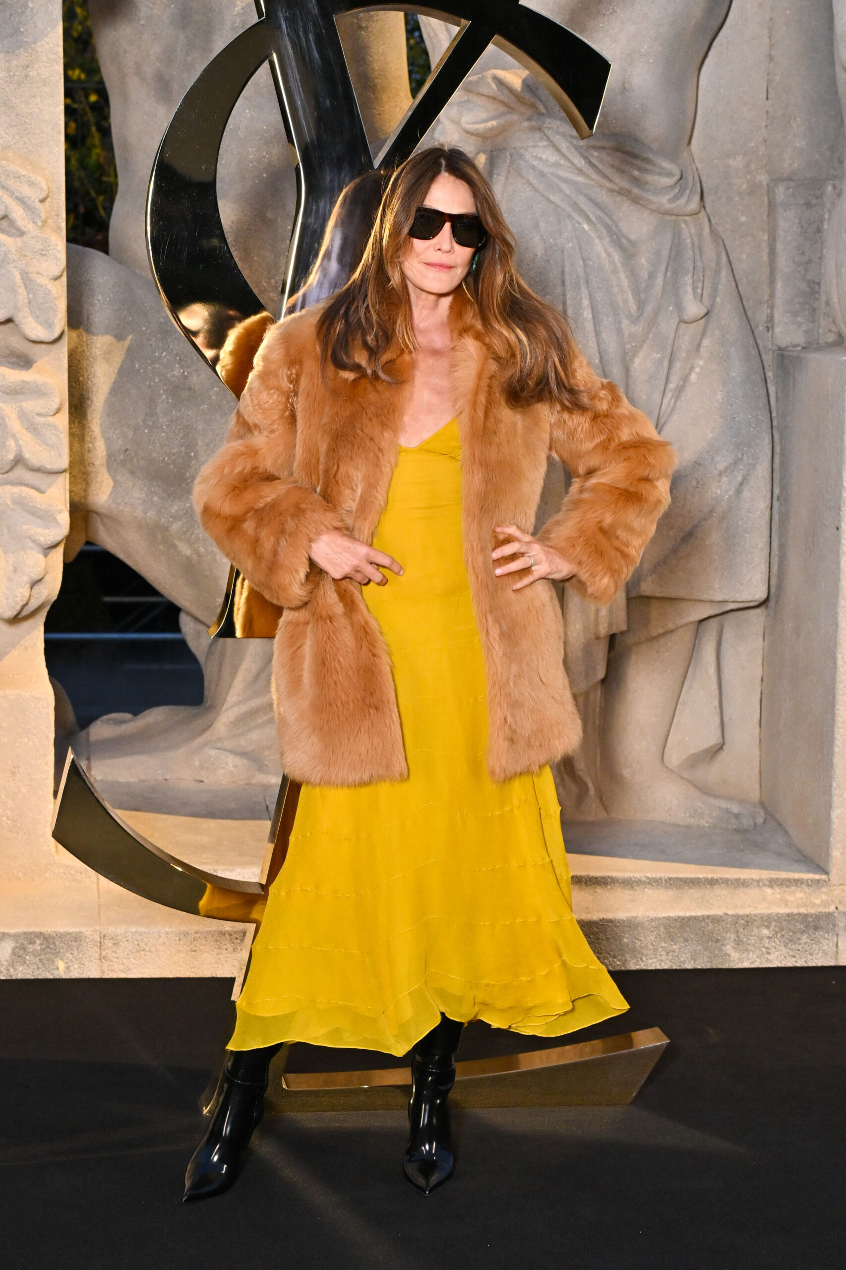 Carla Bruni wearing a sumptuous fur, yellow silk dress, dark shades, and a playfully defiant attitude, photography by Stephane Cardinale Corbis, and courtesy of Getty Images