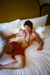 Connor Storrie wears shorts by Prada in bed.