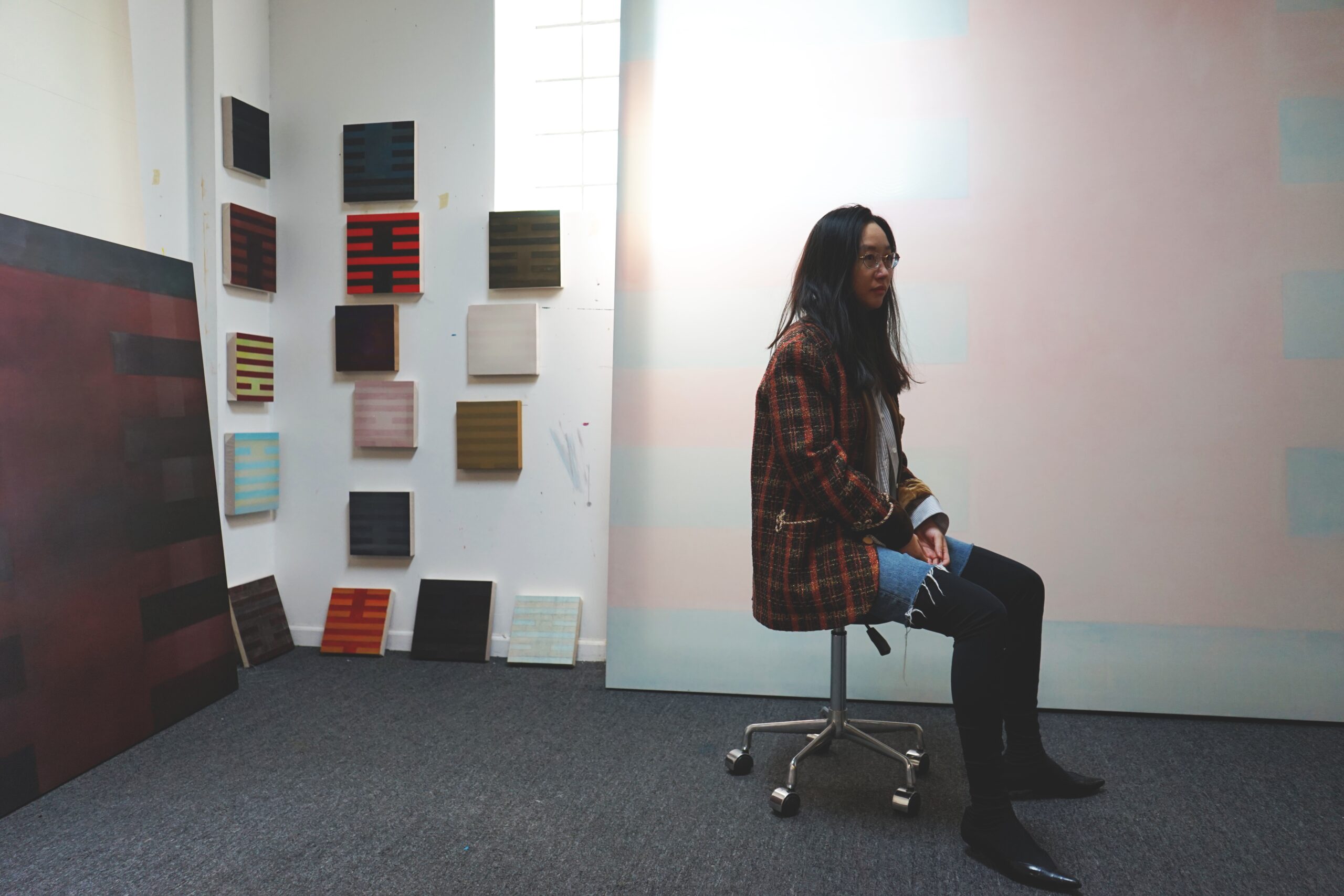 Artist Lea Ke Yi Zheng sits in front of her artwork.