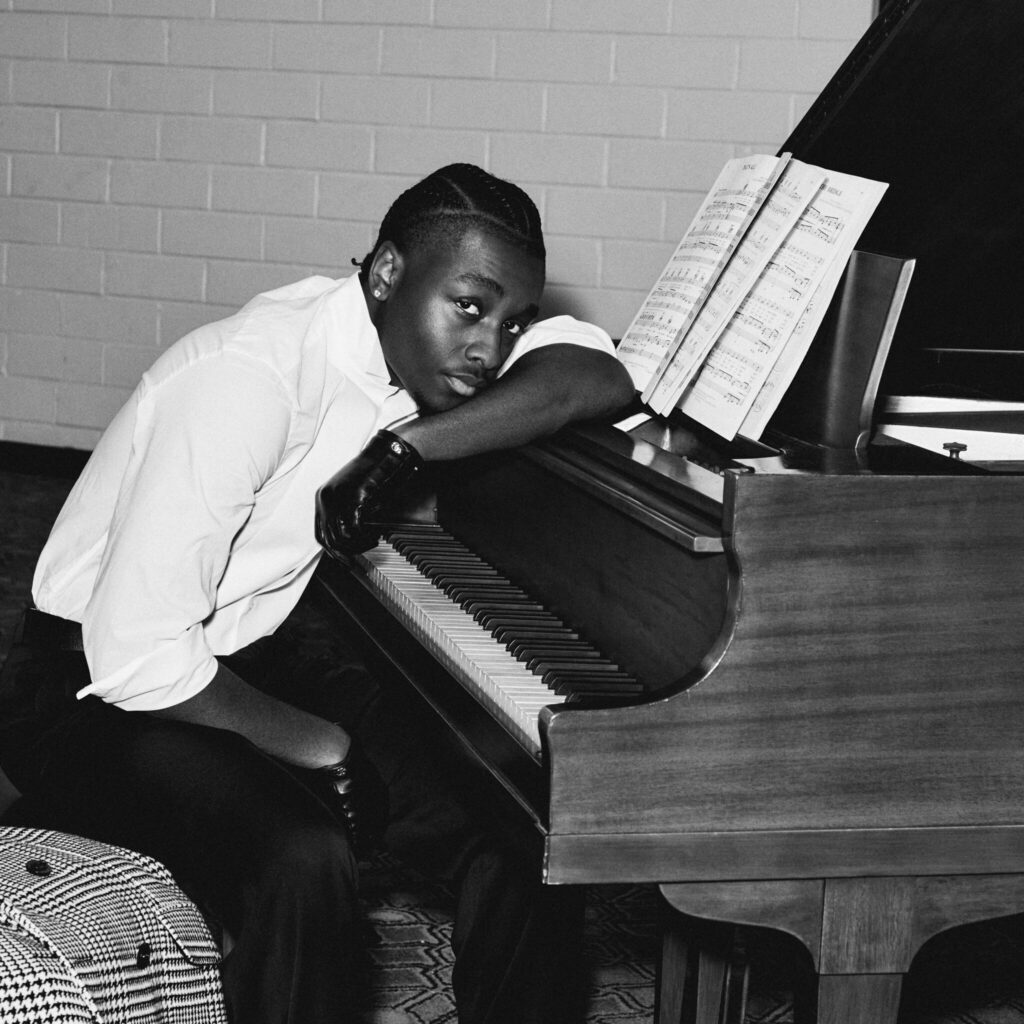 Actor, singer, and Sinners star Miles Canton poses in front of a piano wearing Gucci.