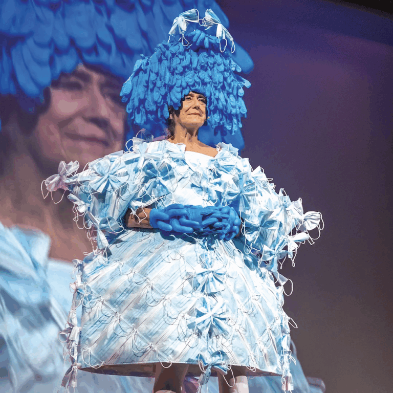 Artist Pat Oleszko wears a fantastical dress made from masks for her performance Masked Mandate.