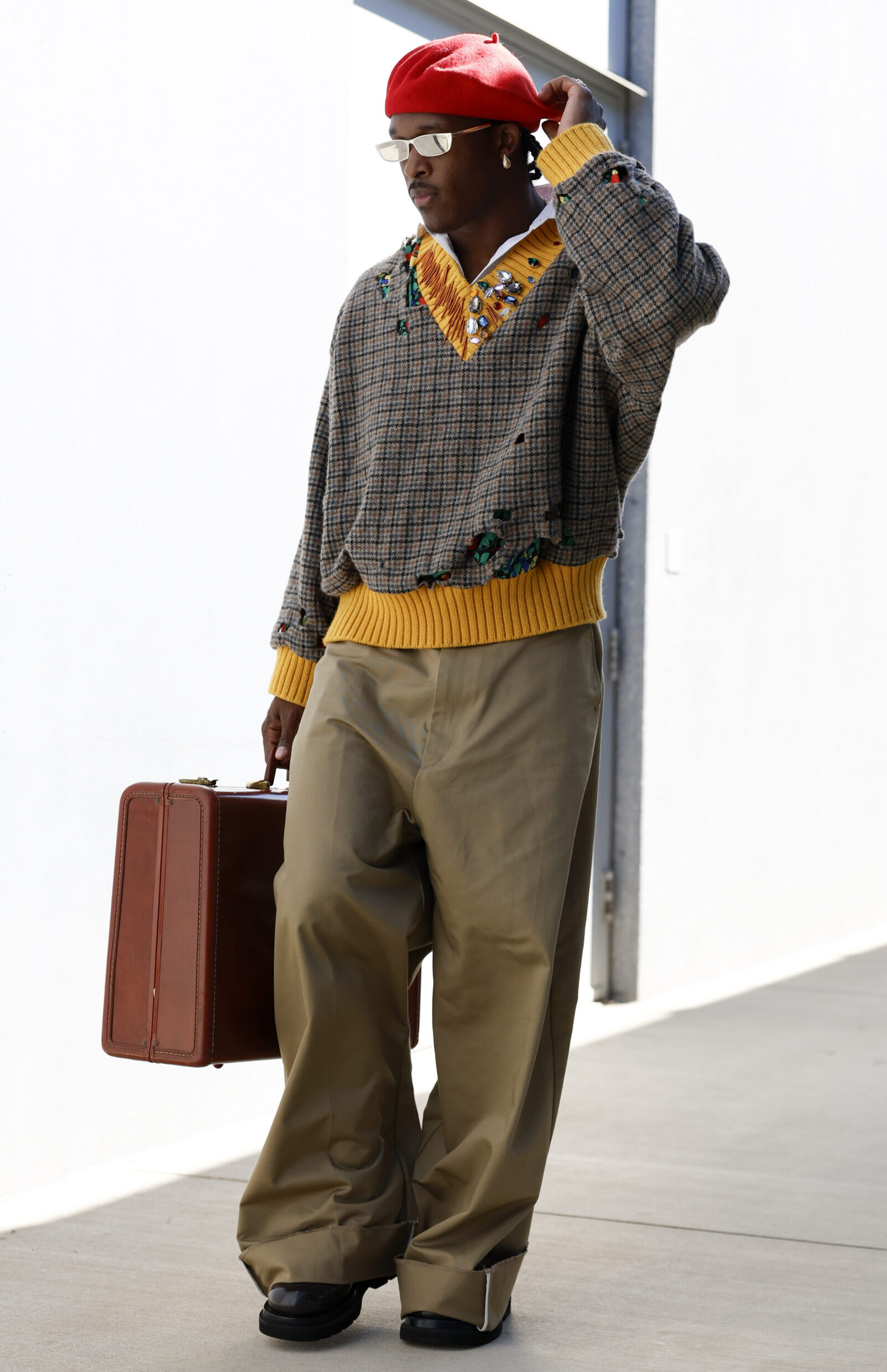 Ray-Ray McCloud III in a red beret, reflective sunglasses, v-neck sweater, brown bag, and black shoes in his tunnel look