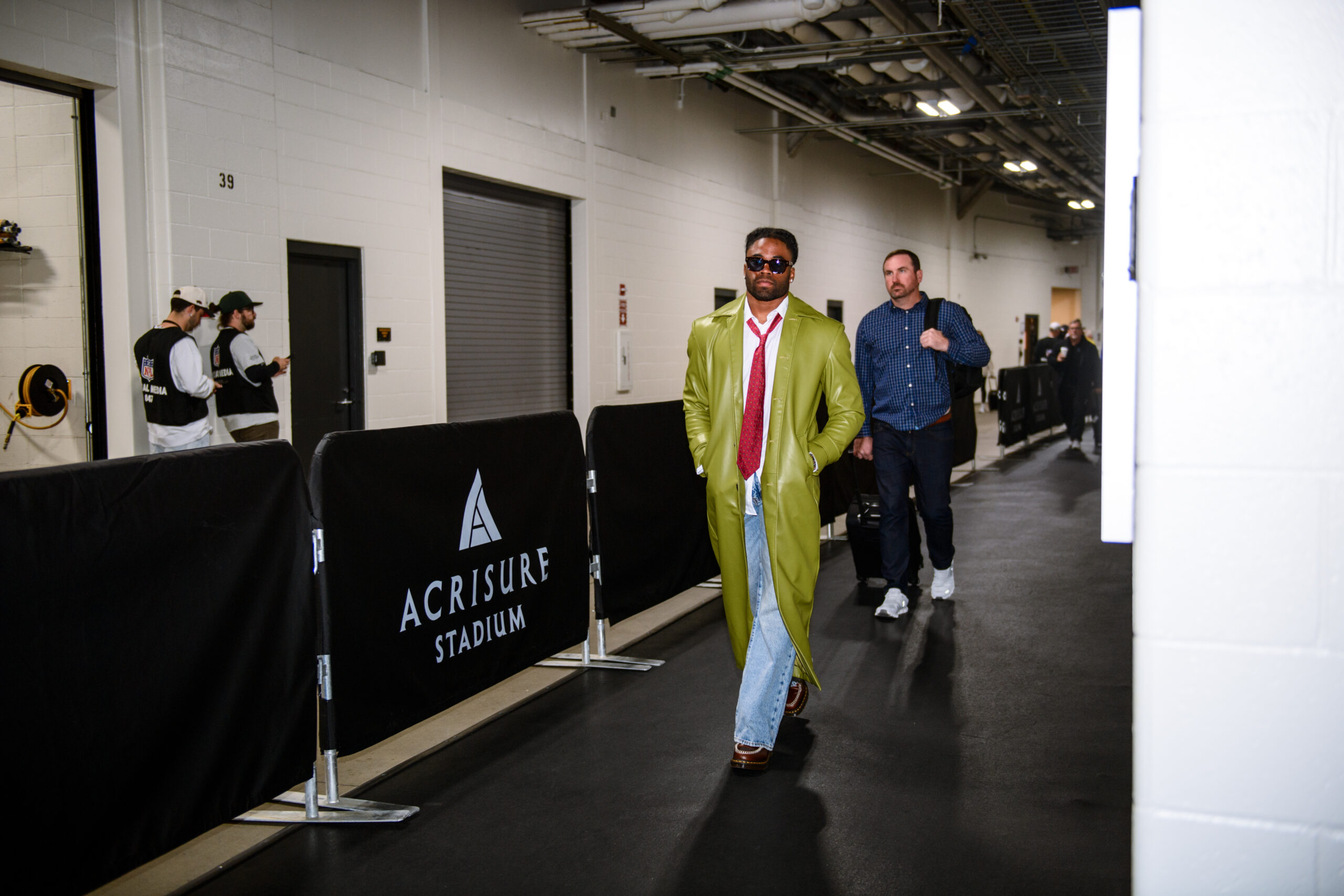 Kenny Moore II of the Indianapolis Colts wearing a green coat, red tie, white shirt, jeans, and brown shoes walking through the tunnel