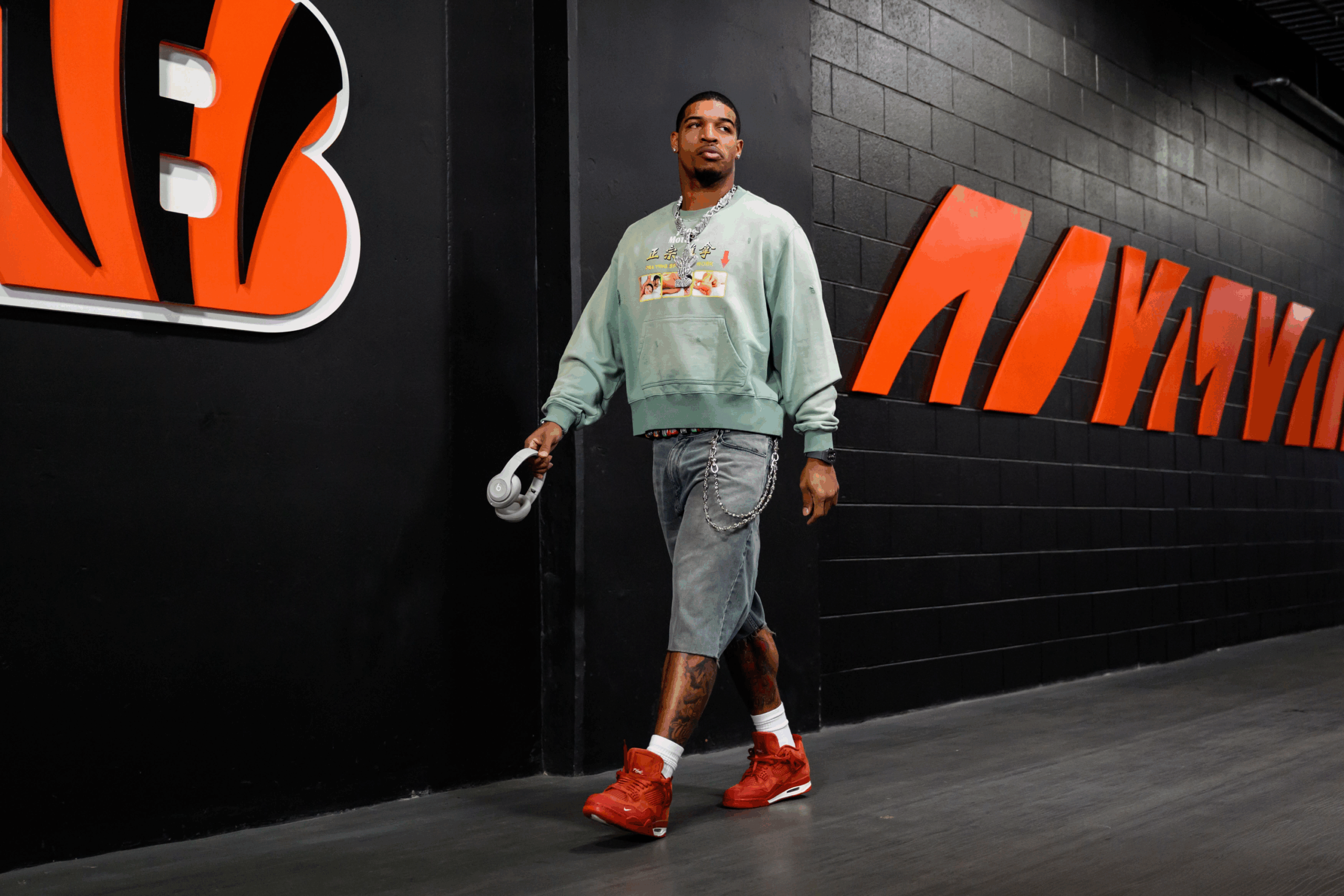 Ja'Marr Chase of the Chicago Bears in a green sweater, denim shorts, and red sneakers walking through the tunnel