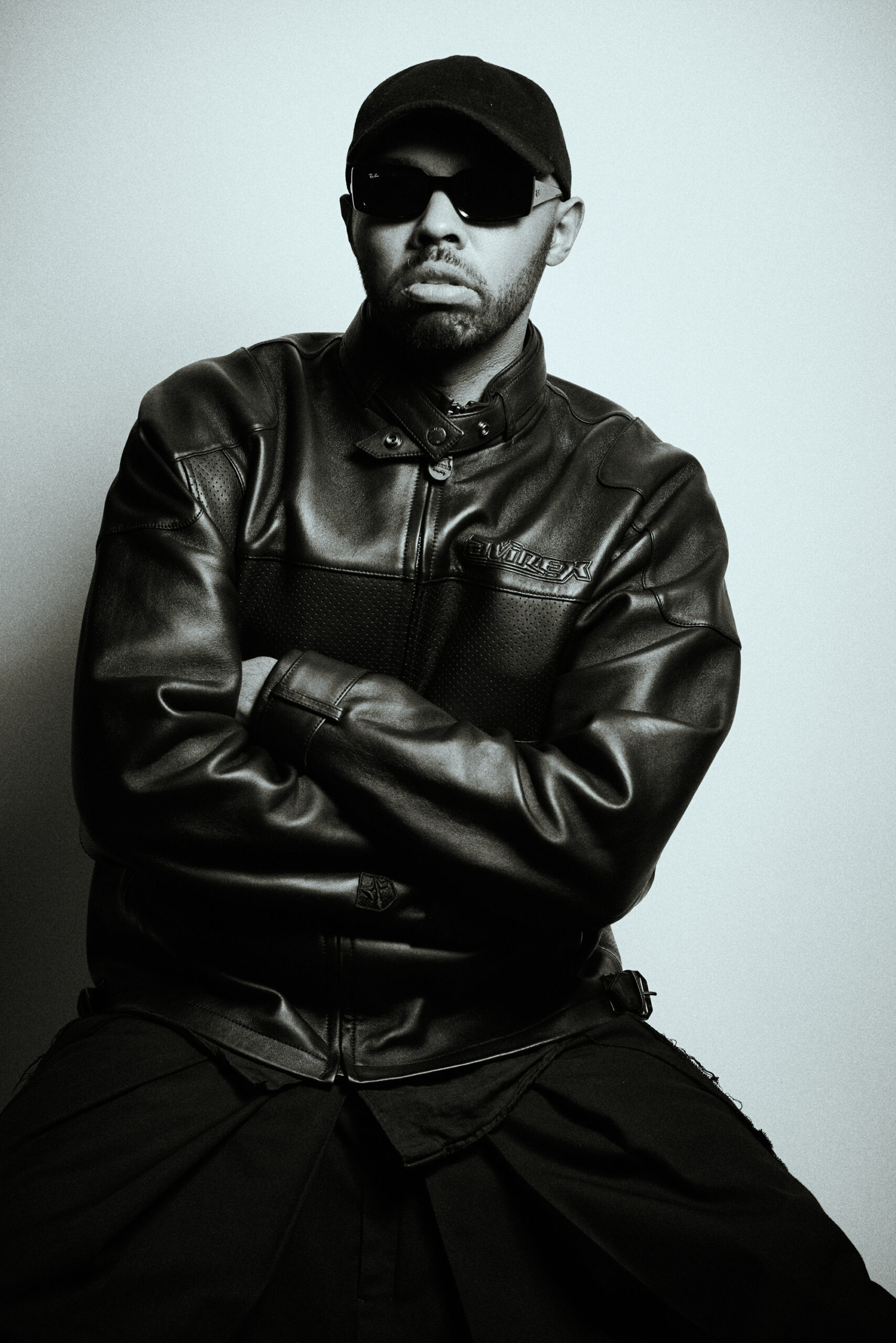 NFL Fashion Editor Kyle Smith in a leather jacket, black slacks, black sunglasses, and a black baseball cap