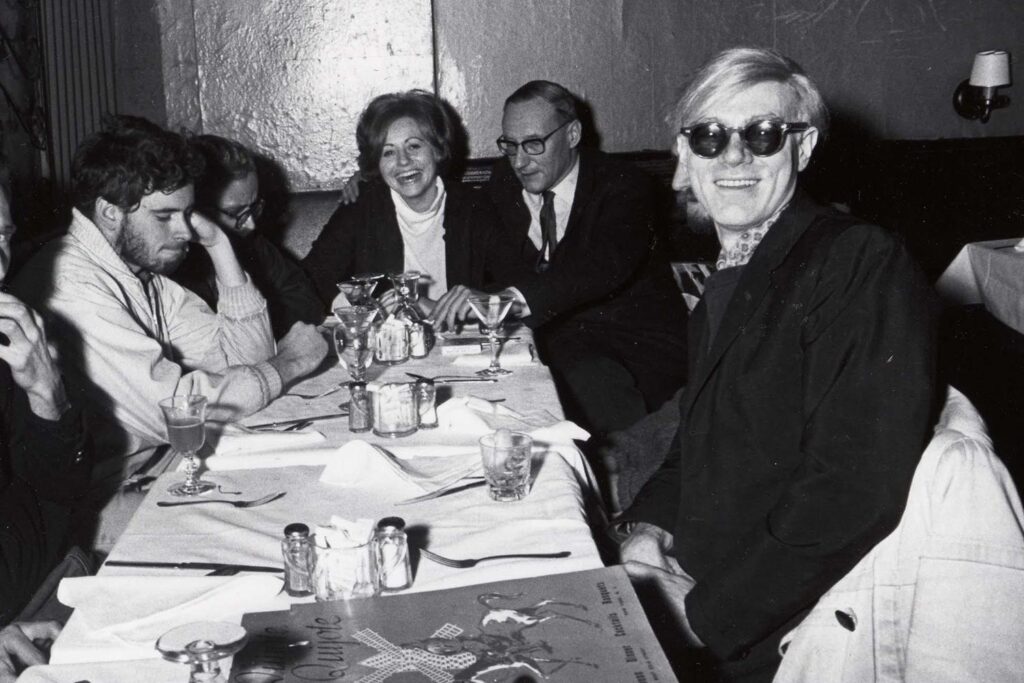 Andy Warhol and friends sit for a meal at the Chelsea Hotel