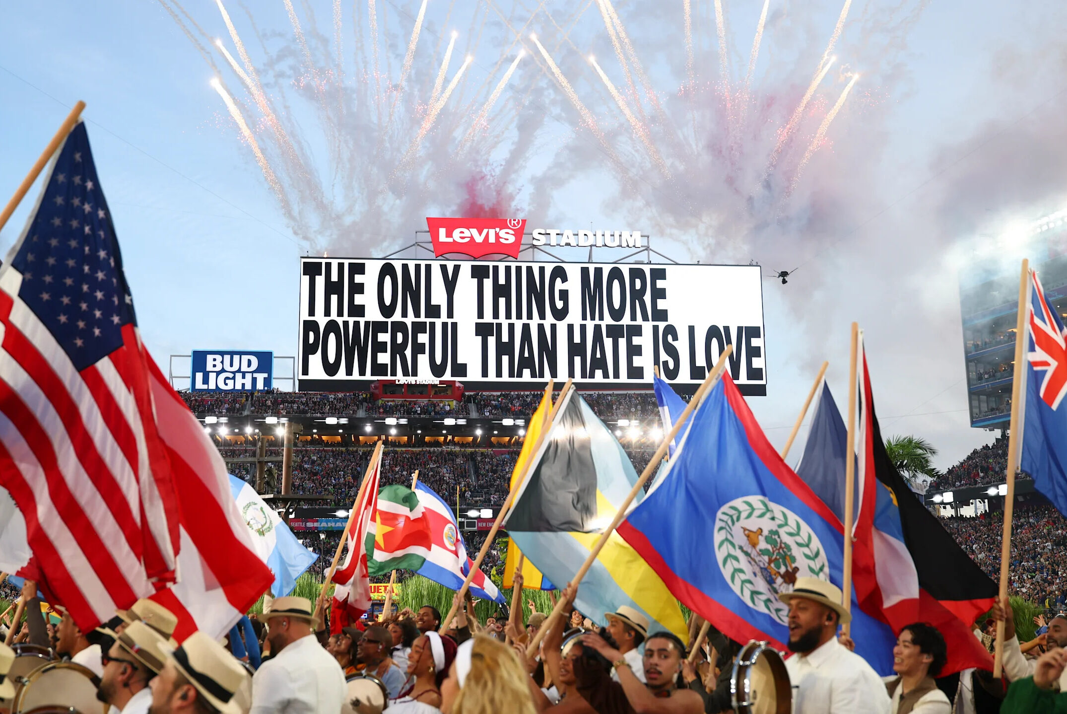 The jumbotron at the Super Bowl depicts the message, "The only thing more powerful than hate is love," as dancers with the flags of Latin America stream onward