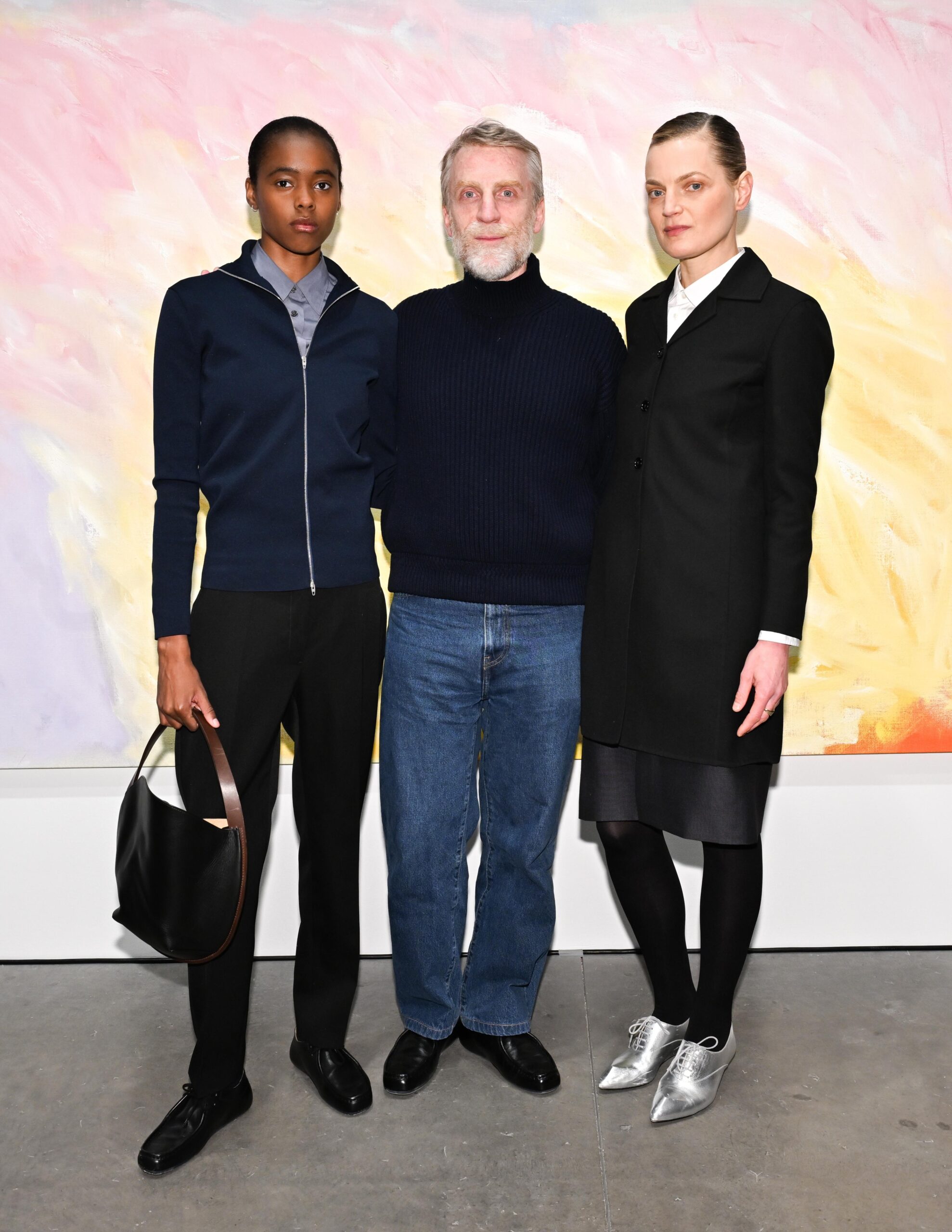 Models Nyla Singleton and Guinevere Van Seenus poe with Jil Sander designer Simone Bellotti at Marianne Goodman Gallery in front of a canvas