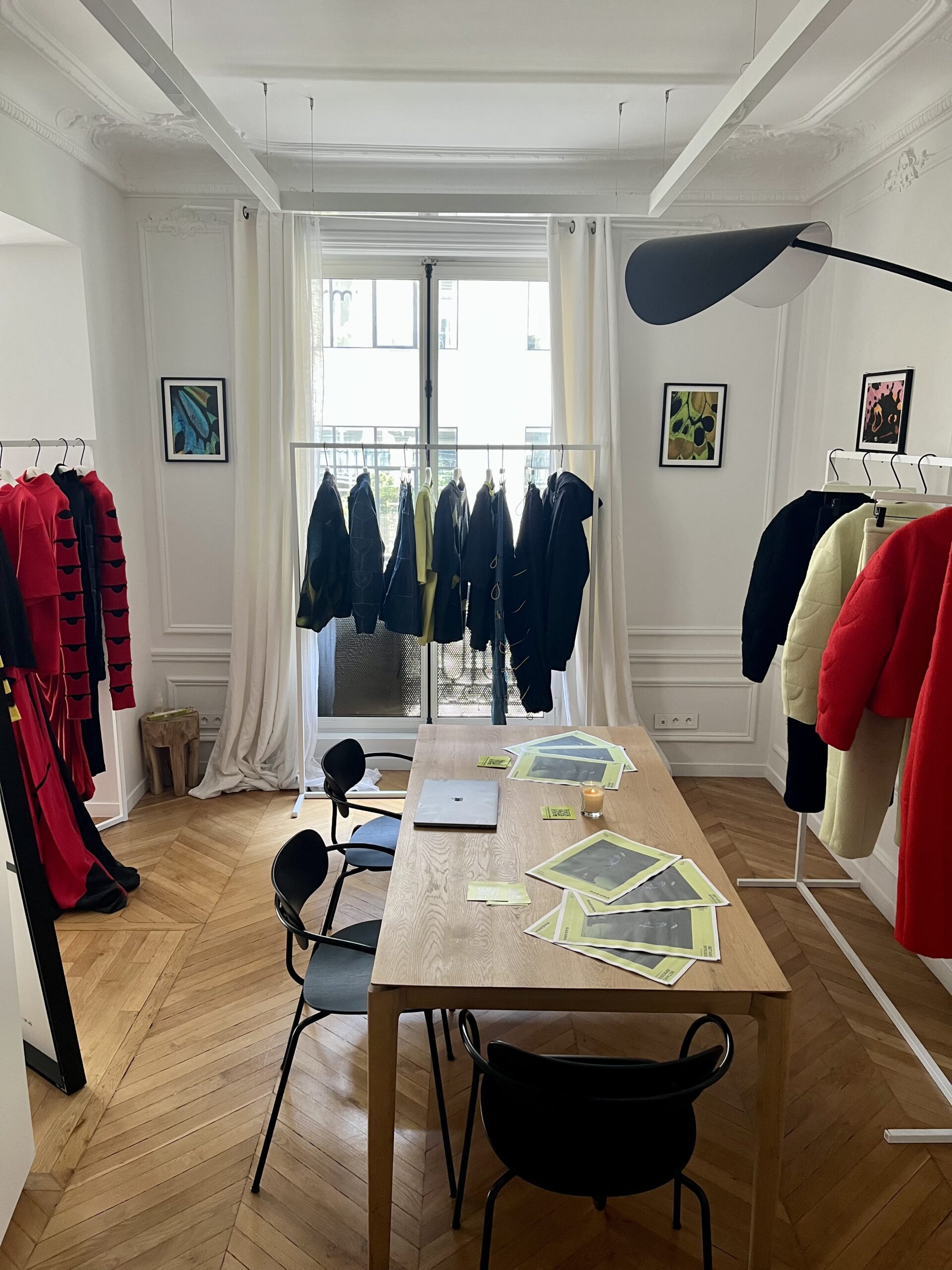 Racks of clothes and a central worktable fill the space of the RAEANA studio