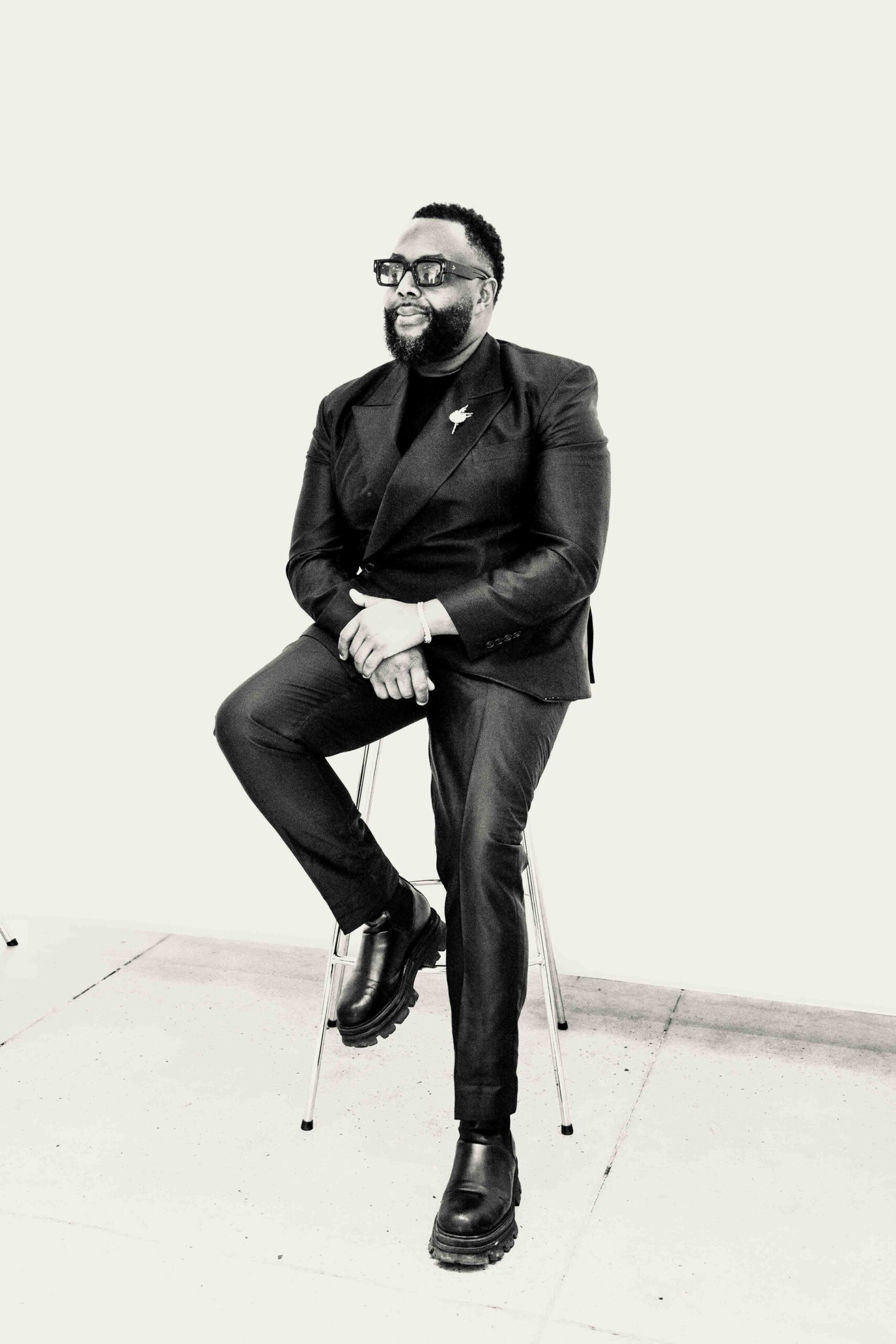 Jimmy LaTouché poses for a portrait in a suit, sunglasses, and boots