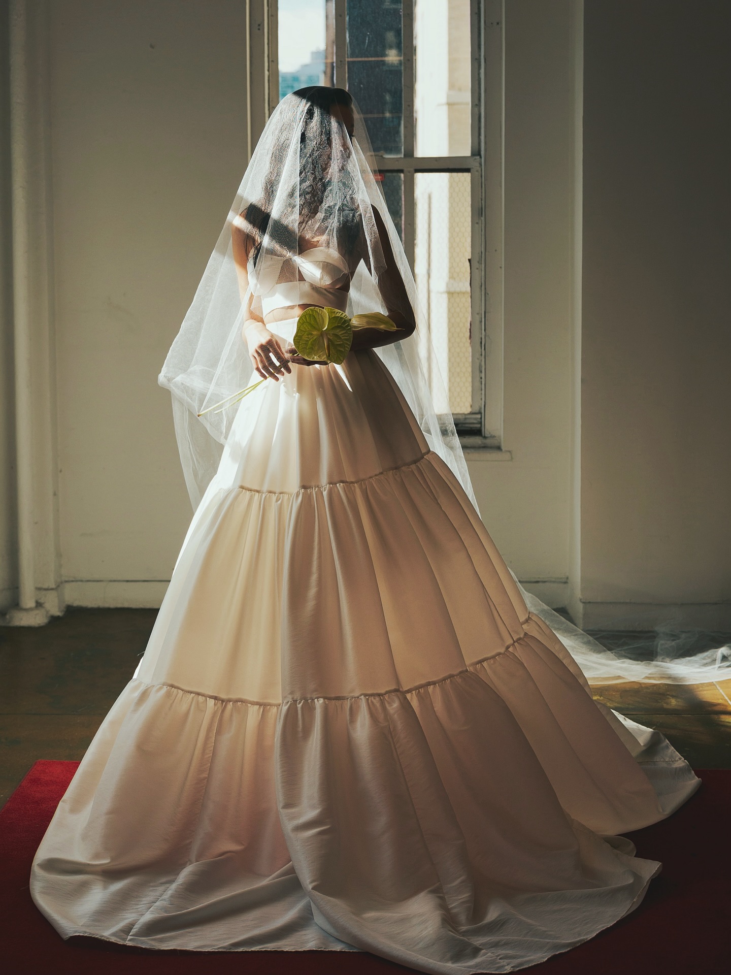 A model wears a white Scorcésa wedding gown in a showroom on a red carpet