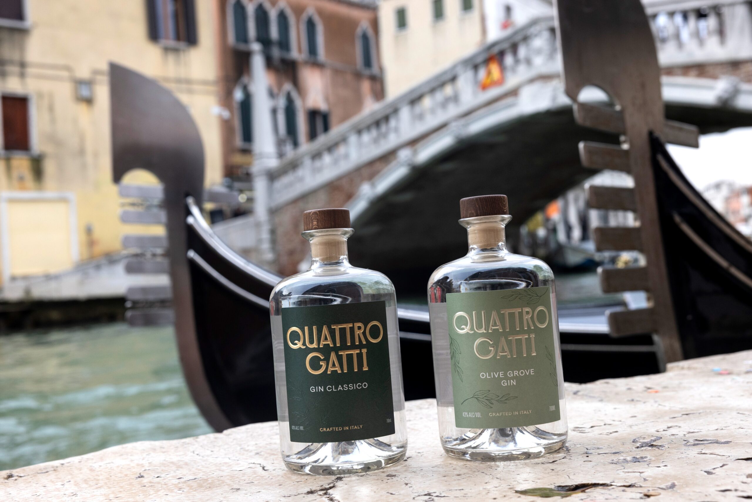 Two bottles of Quattro Gatti gin rest on a canal in Venice