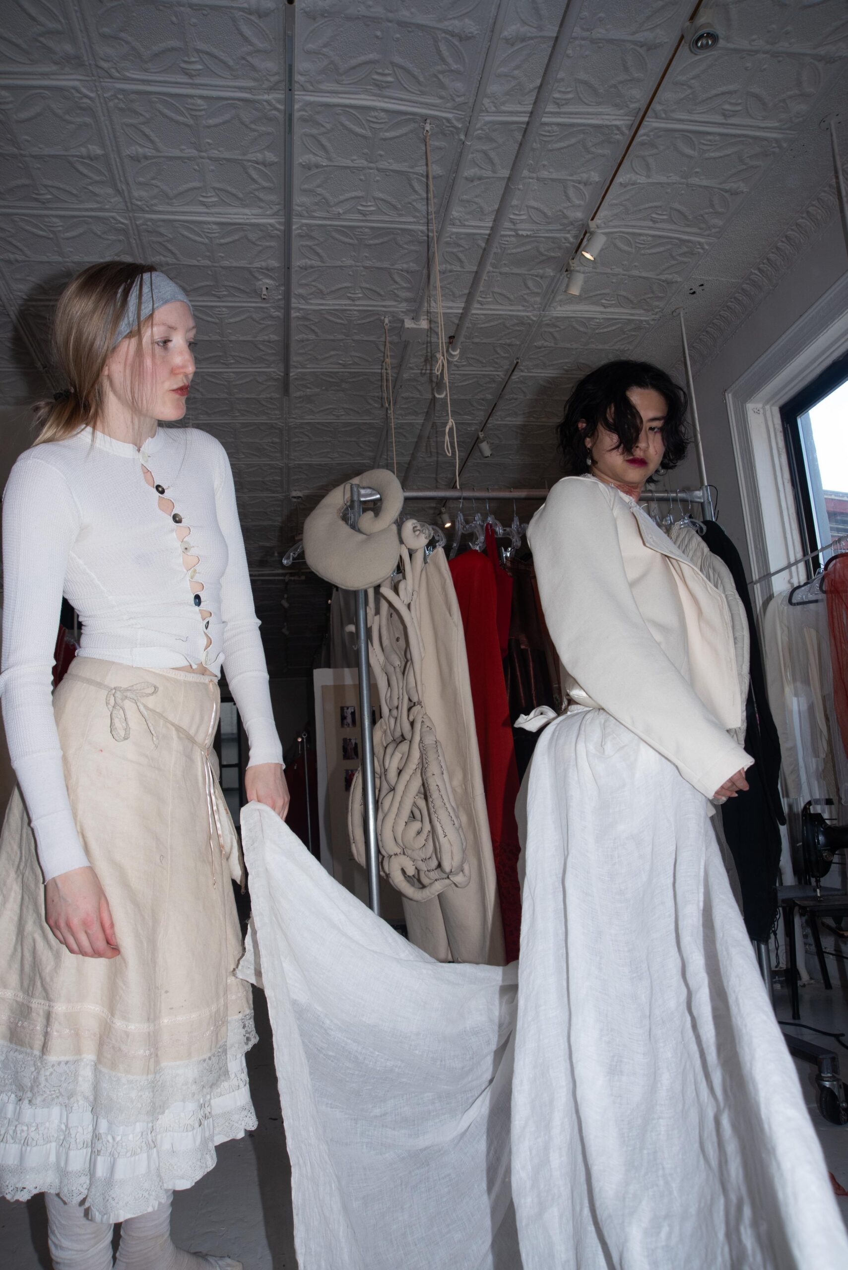 Zoe Gustavia Anna Whalen dresses Cato Young in her garments in a white-washed studio backed by racks and a tinned ceiling