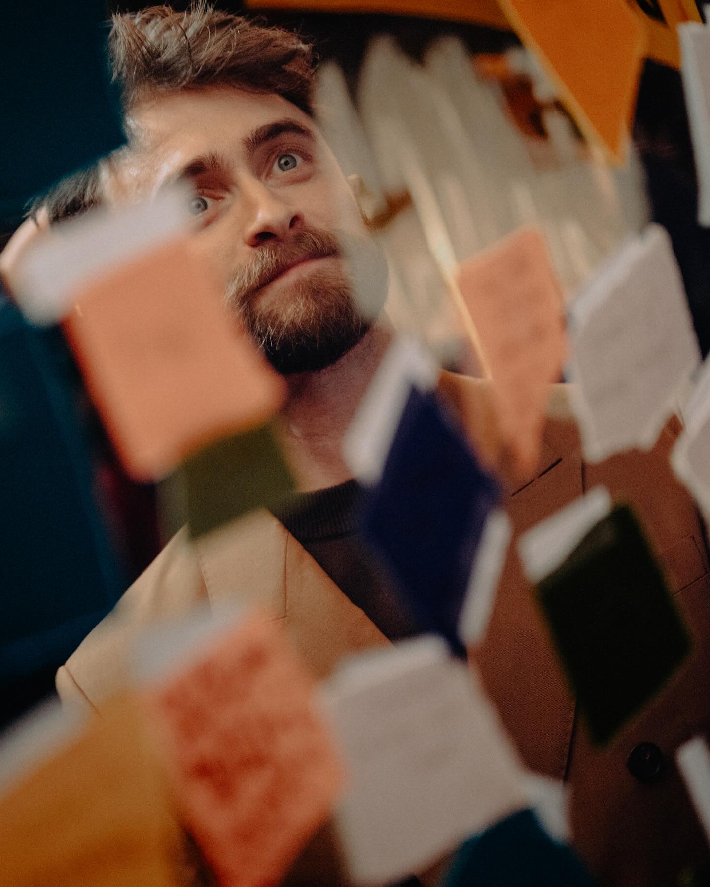 Daniel Radcliffe performs in front of a mirror packed with sticky notes and paper