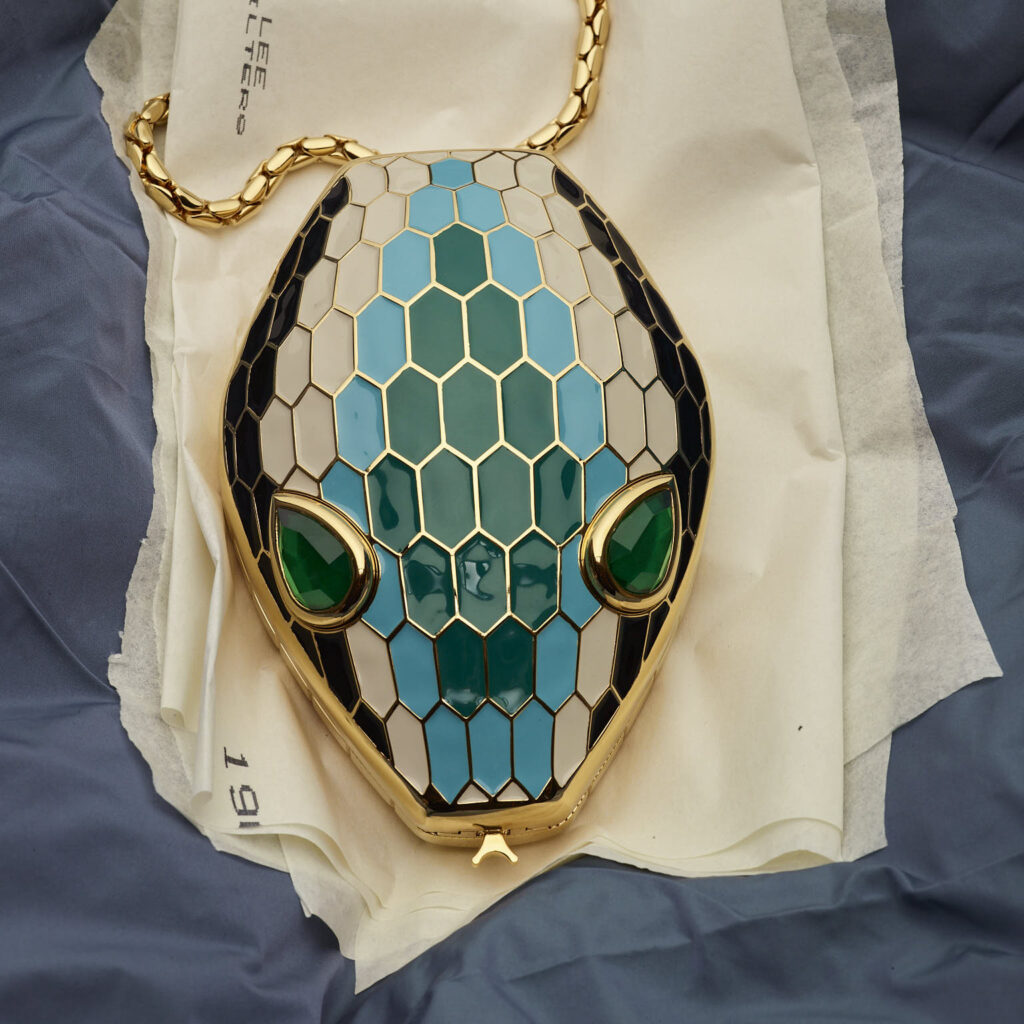 A shot of the Bvlgari Serpenti Minaudière on cream cloth and a blue spread