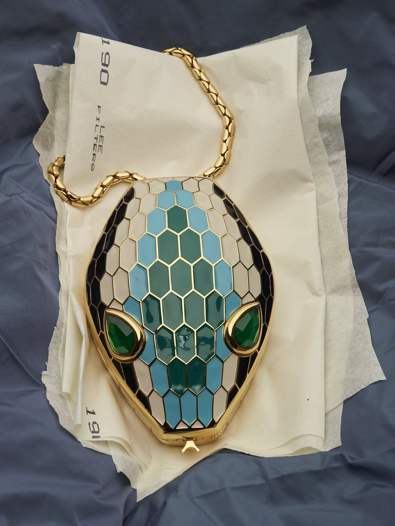 A shot of the Bvlgari Serpenti Minaudière on cream cloth and a blue spread