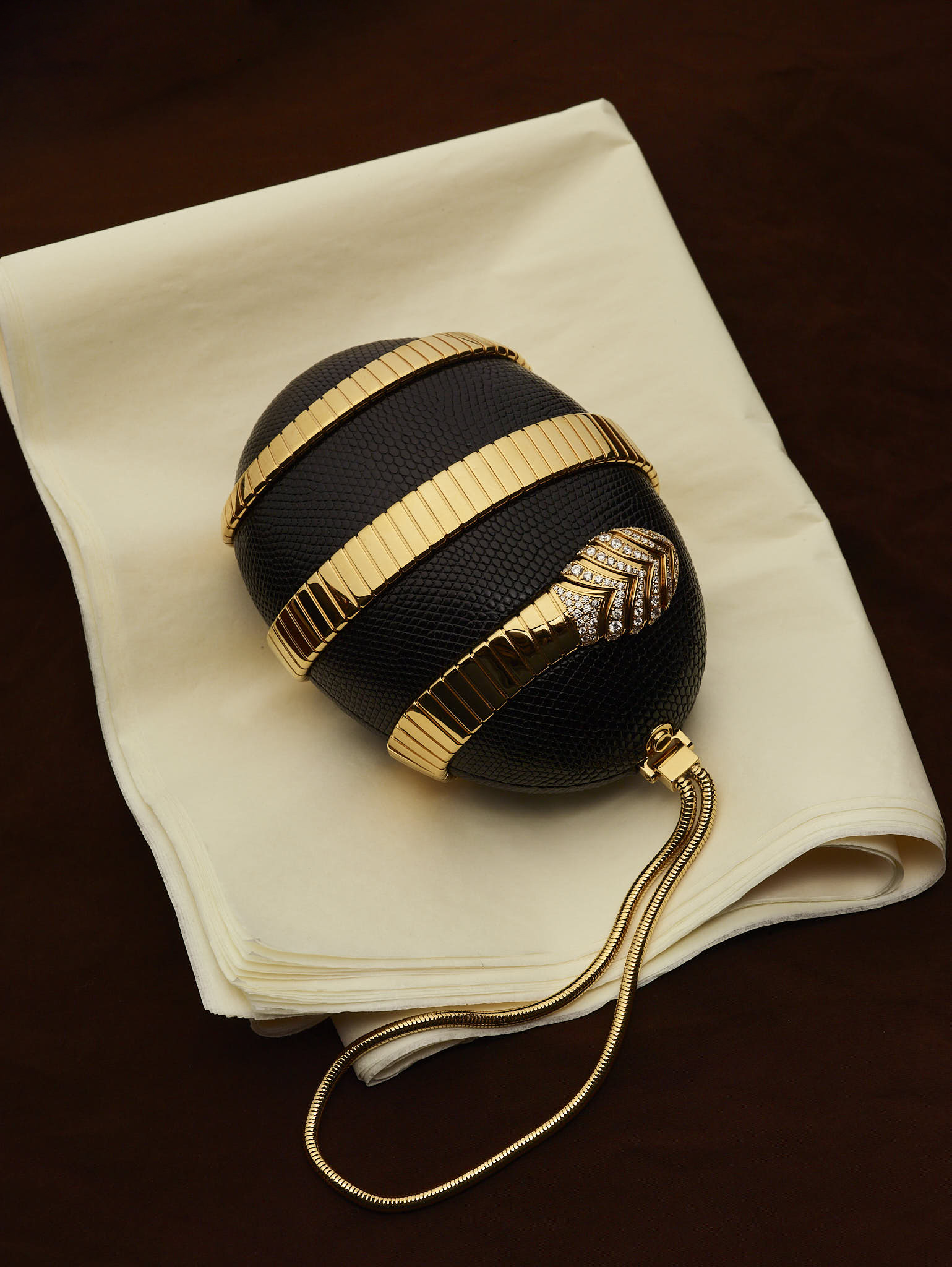 A shot of the Bvlgari Tubogas Minaudière on cream cloth