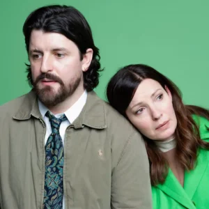 Kate Arrington and Shane McNaughton pose for a promotional portrait against a green background