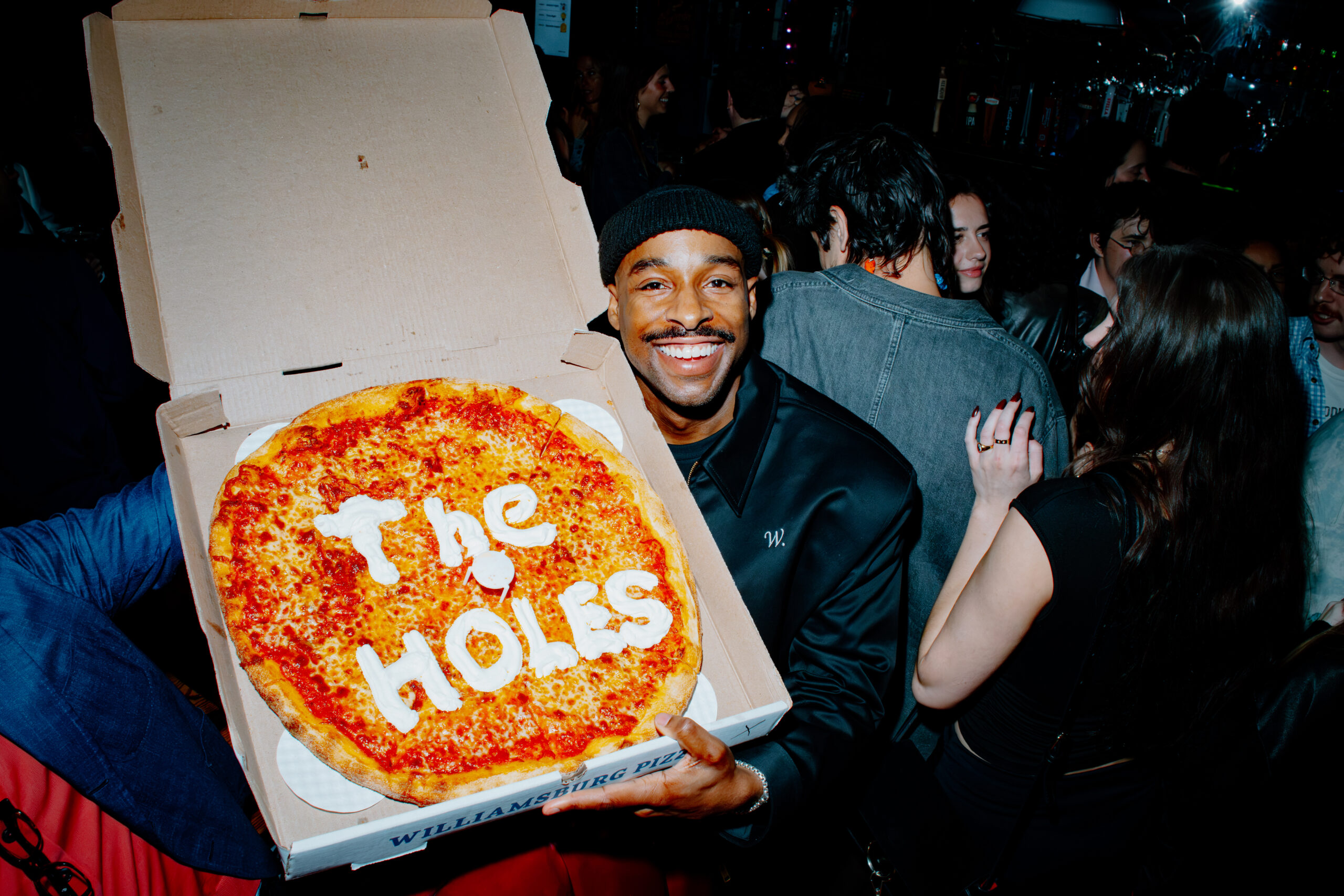 Actor Grantham Coleman holds a pizza decorated with “The Holes” at the event