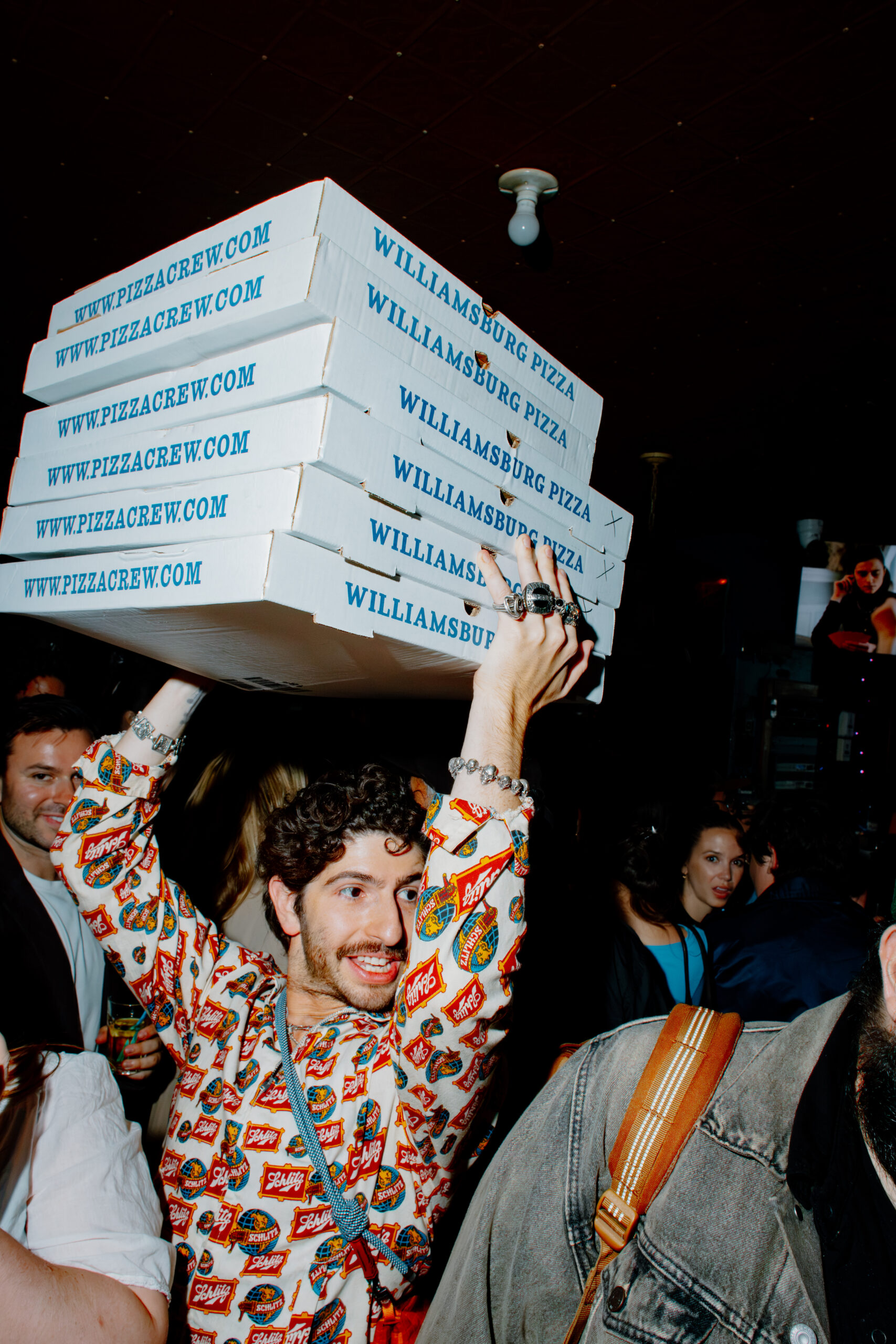 Pizza) Russell Kahn holds a stack of Williamsburg Pizza boxes above his head.